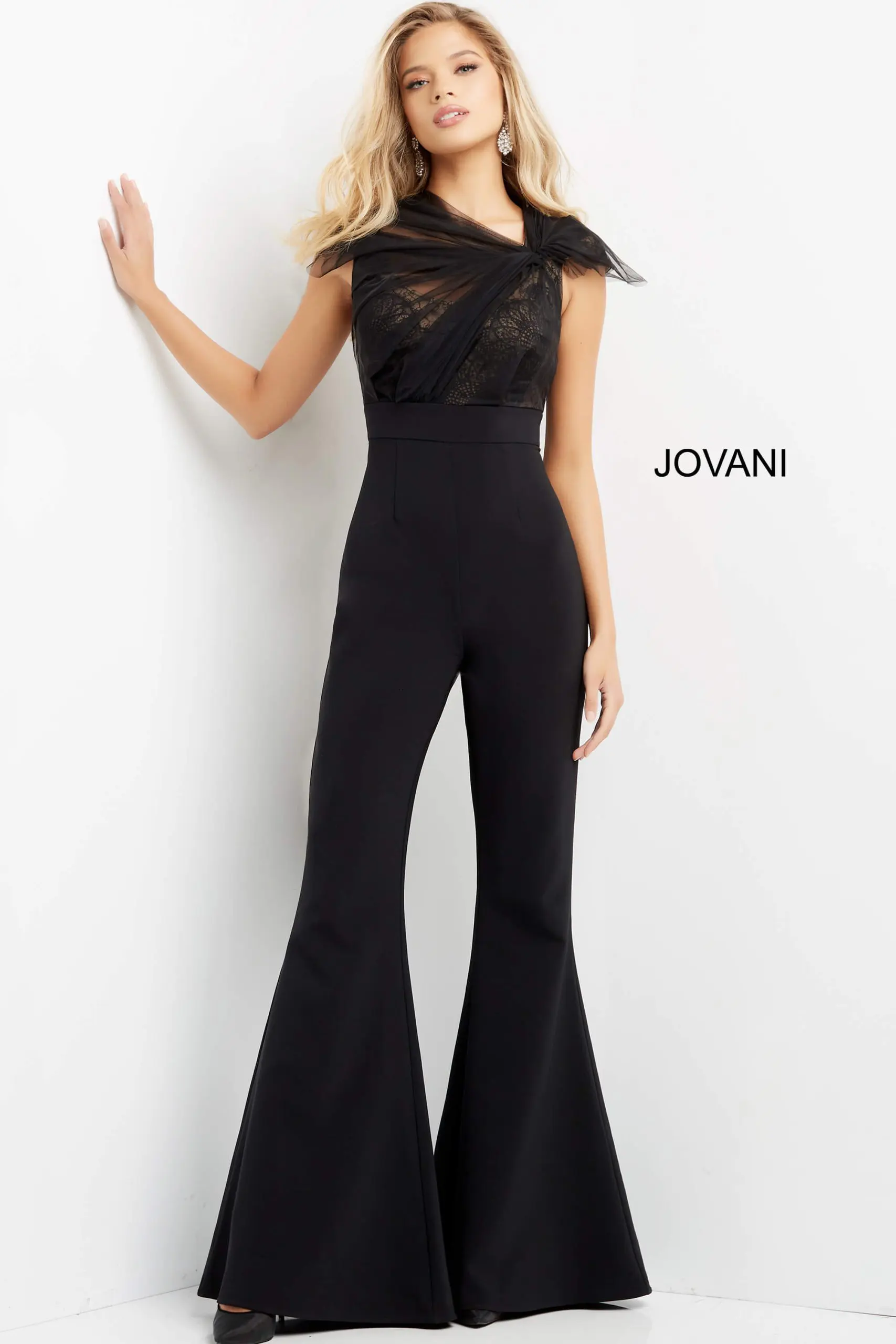 Model wearing Jovani 05676 black jumpsuit with lace detailing and wide-leg pants.