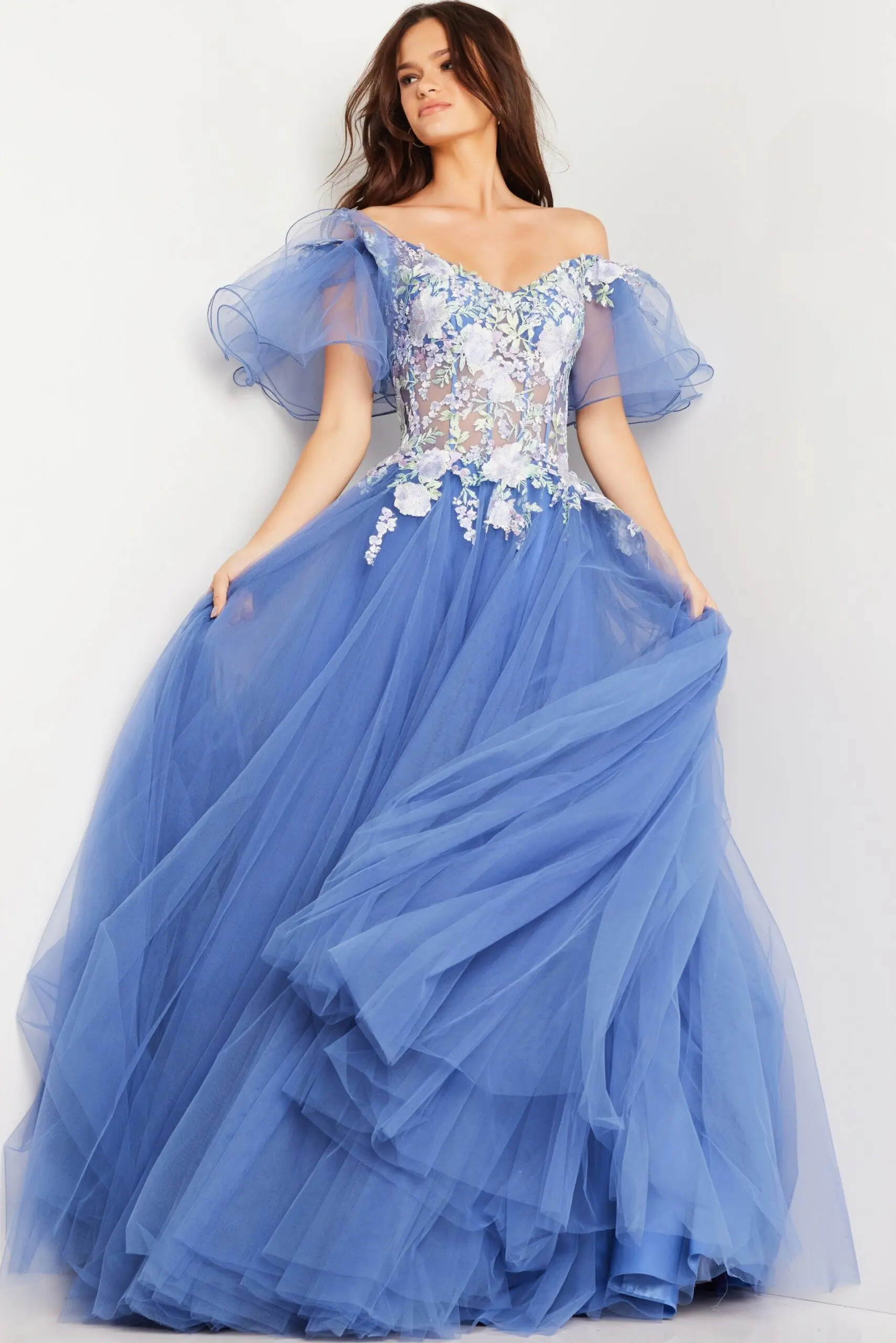 Model wearing Jovani 24575 blue ball gown with floral appliqués.