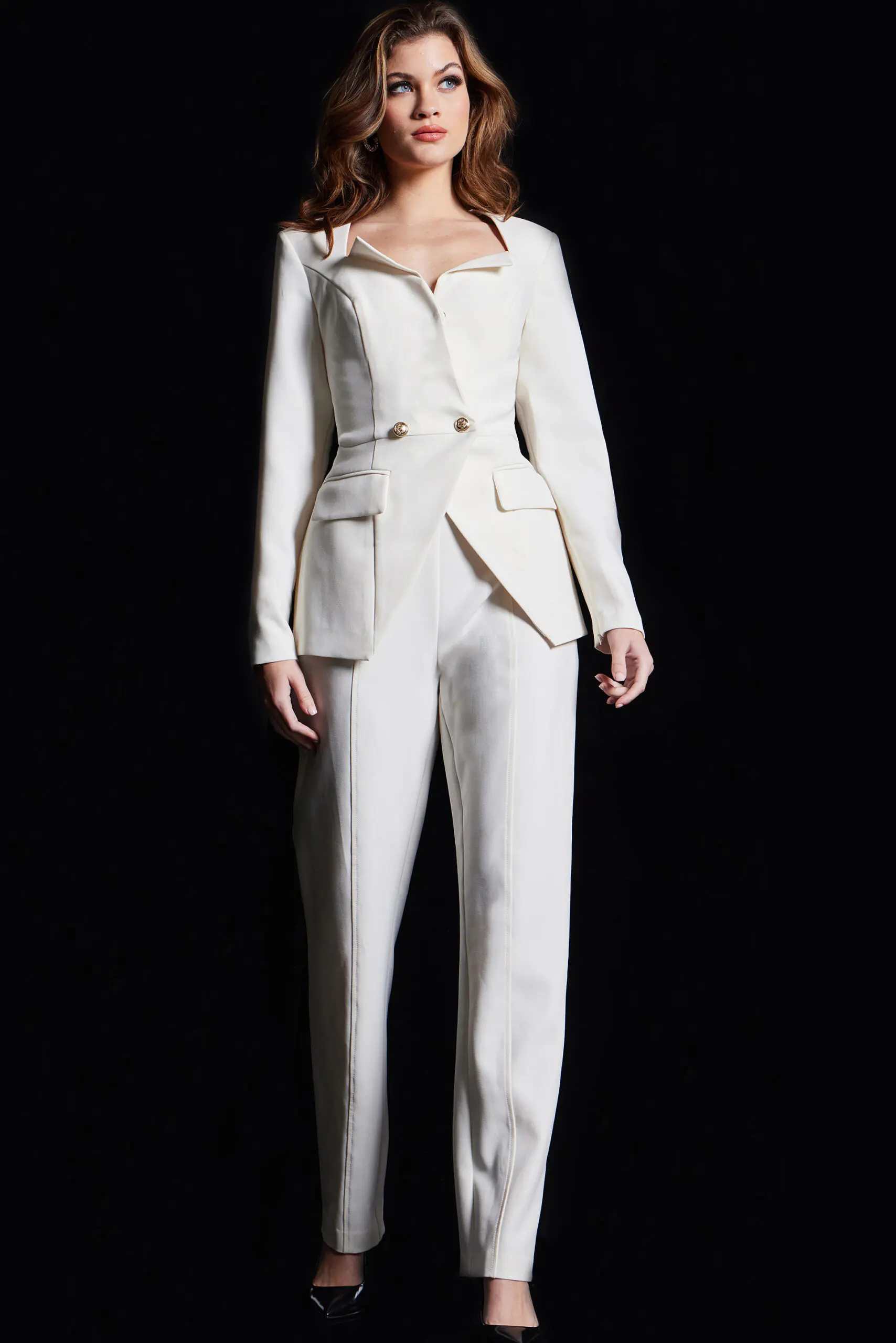 Model wearing Jovani 37031 ivory jumpsuit featuring a tailored silhouette with gold button details and a notch neckline.