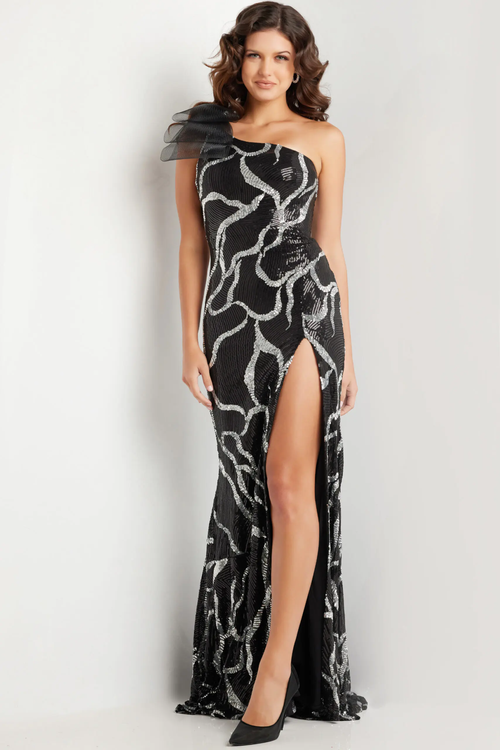 Model wearing Jovani 38377 black gown with asymmetric neckline, sequins, and high slit