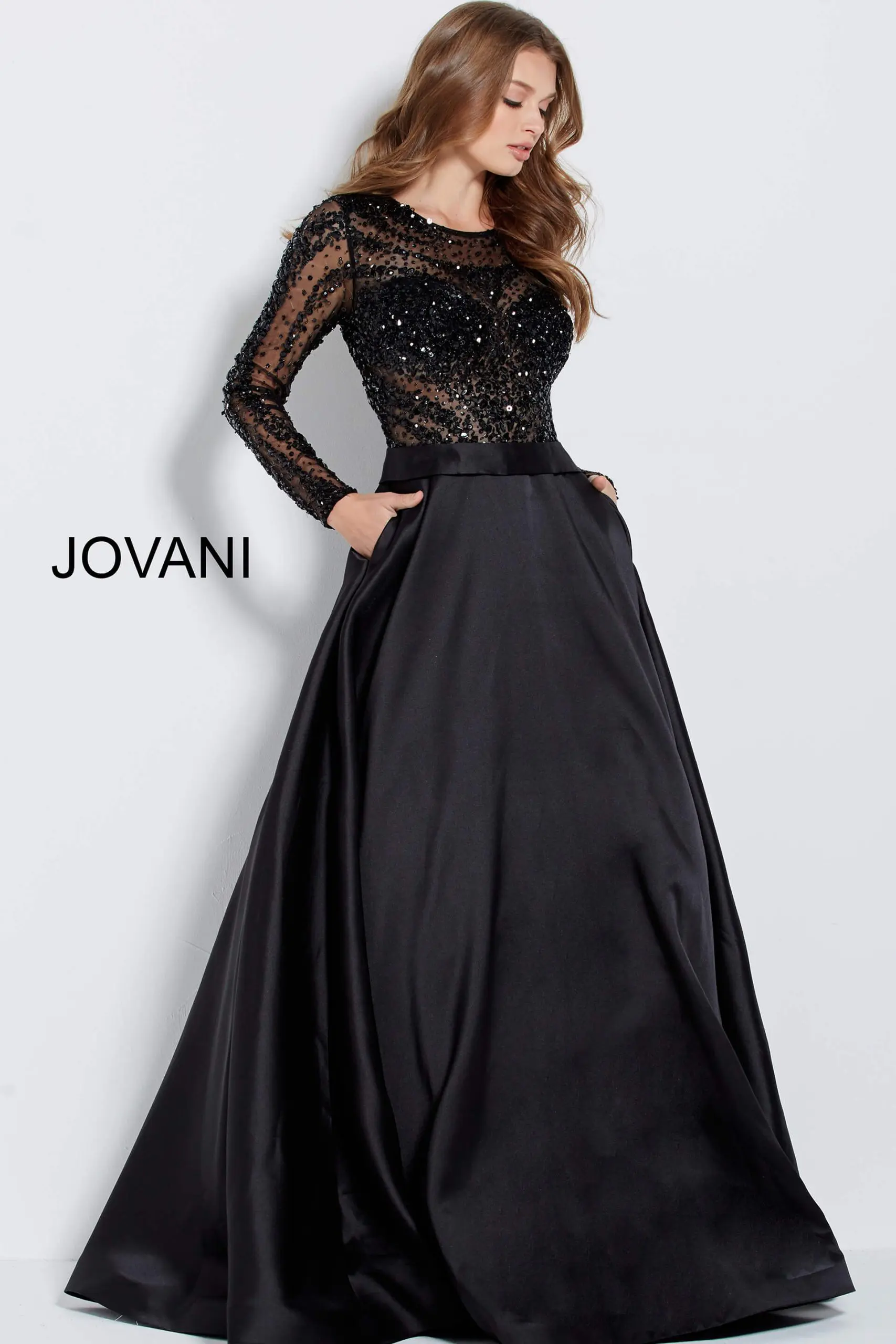 Model wearing Jovani 46066 black gown with beaded bodice and long sleeves.
