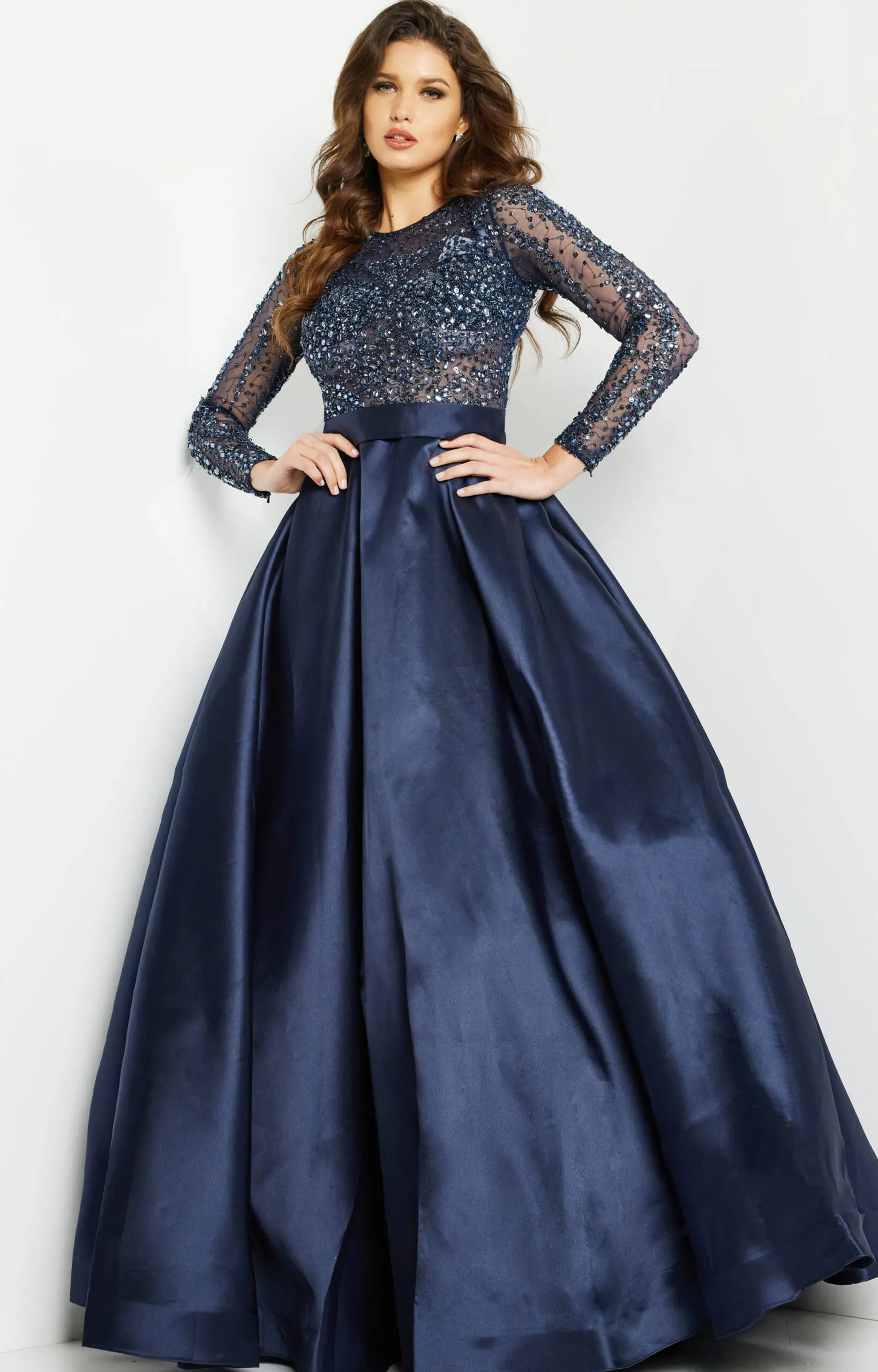 Model wearing Jovani 46066 navy ball gown with sequined bodice and long sleeves