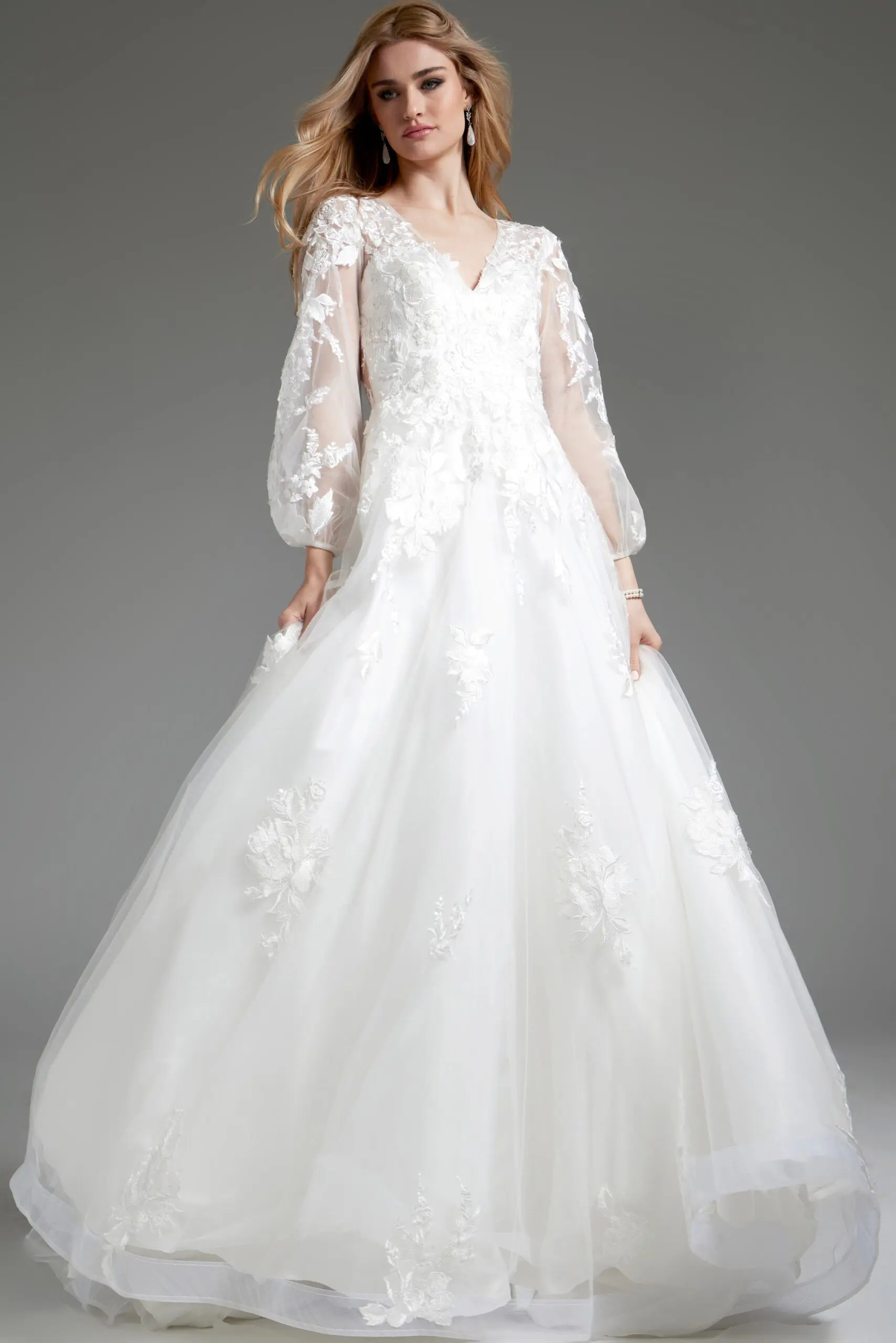 Model wearing Jovani JB25731 off-white gown with V-neck and sheer long sleeves.