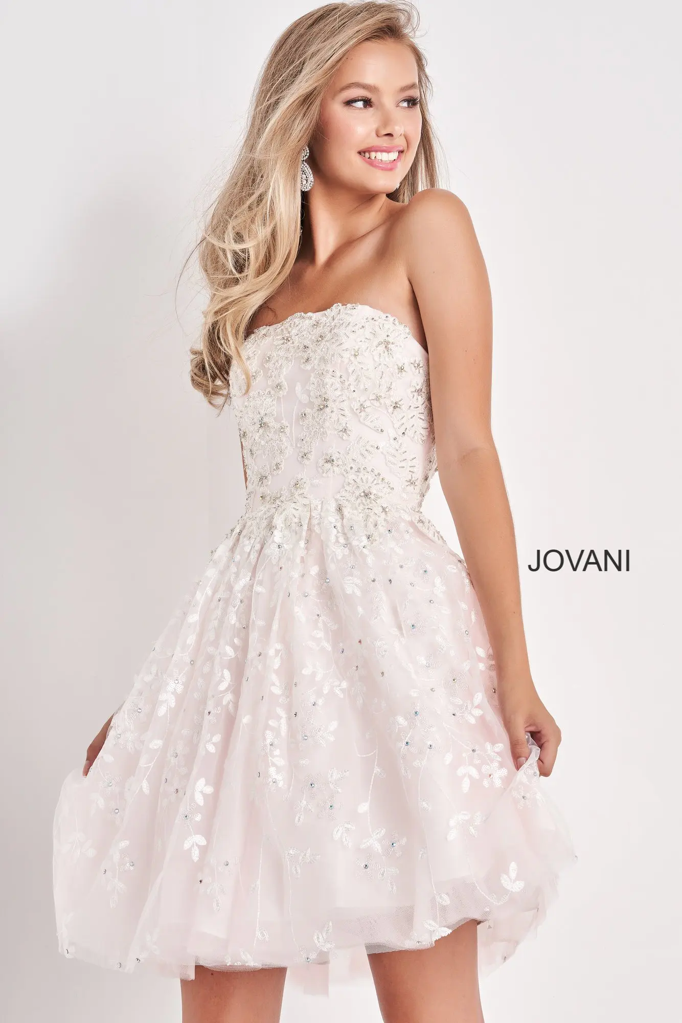 Model wearing Jovani K68026 white dress, front view with strapless neckline and floral embellishments.