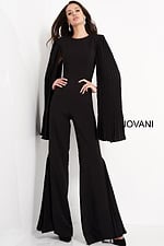 Model wearing Jovani 00756 black jumpsuit with pleated cape sleeves, front view.