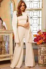 Model wearing Jovani 00756 ivory jumpsuit with pleated cape sleeves, side front view.