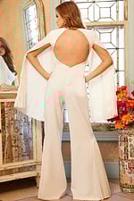 Model wearing Jovani 00756 ivory jumpsuit with pleated cape sleeves, back view.