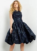 Model in Jovani 05016 navy dress with textured pattern and cap sleeves.