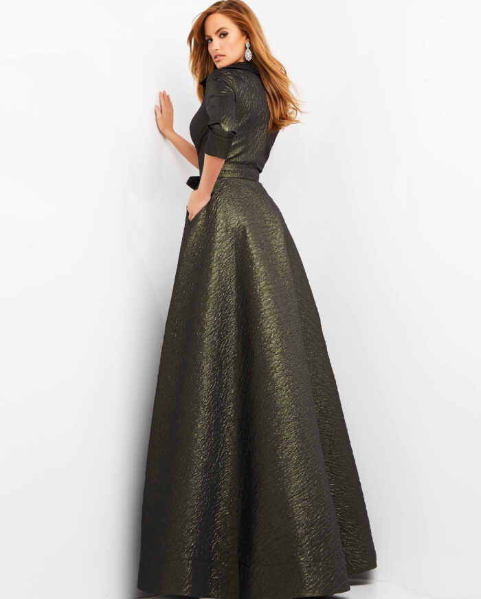 Model elegantly posing in a Jovani 05075 green dress with three-quarter sleeves.