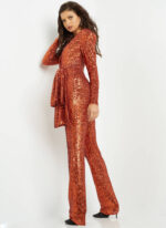 Model in Jovani 05345 orange sequin jumpsuit, side view emphasizing draped peplum and long sleeves.