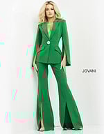 Model wearing Jovani 06922 emerald green jumpsuit with cape sleeves and brooch detail, front view.