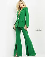 Model wearing Jovani 06922 emerald green jumpsuit with cape sleeves and brooch detail, front view.