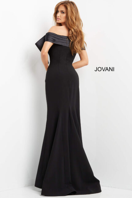 Model wearing Jovani 07014 black off-the-shoulder gown with large bow, back view.