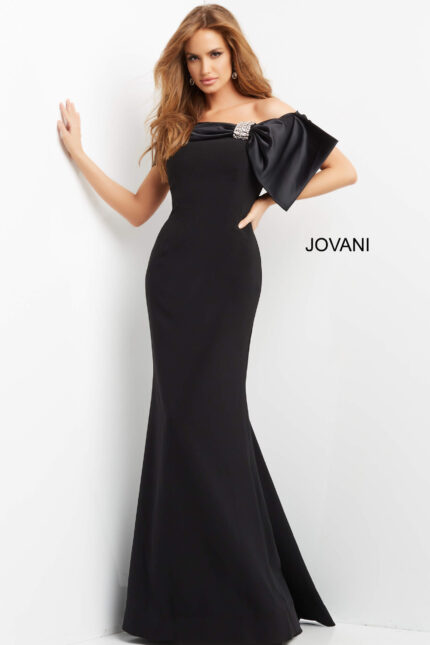 Model wearing Jovani 07014 black off-the-shoulder gown with large bow and embellishment, front view.