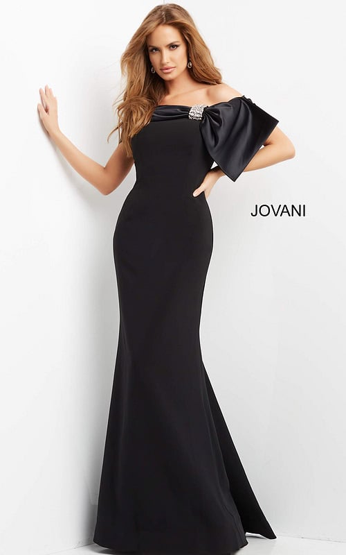 Model wearing Jovani 07014 black off-the-shoulder gown with large bow and embellishment, front view.