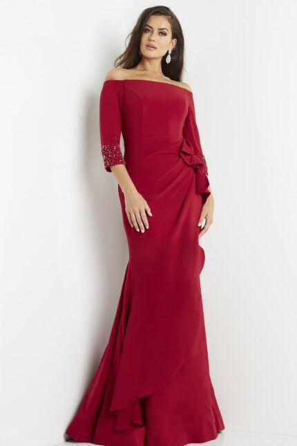 Model wearing Jovani 08699 red gown, showcasing beadwork sleeves and bow accent.