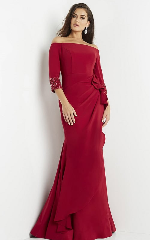 Model wearing Jovani 08699 red gown, showcasing beadwork sleeves and bow accent.