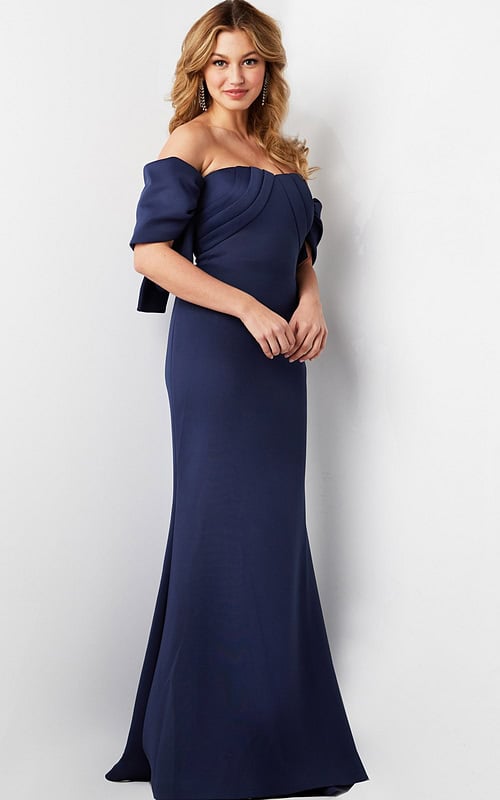 Model wearing Jovani 09064 navy dress with off-the-shoulder design and pleated bodice.
