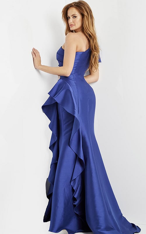 Back view of model wearing Jovani 09201 blue gown with ruffle design and one-shoulder puff sleeve.