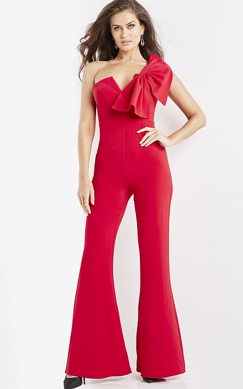Model wearing Jovani 09525 red jumpsuit, front view with one-shoulder bow detail.