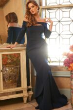 Model wearing Jovani 09623 navy gown with elegant off-shoulder design and cutout.