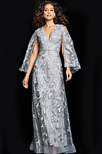 Model wearing Jovani 09809 silver gown with V-neckline and cape sleeves.