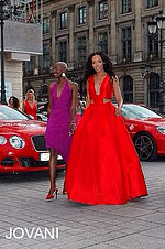 Two models, one in Jovani 22613 royal gown and another in a red dress, walking together