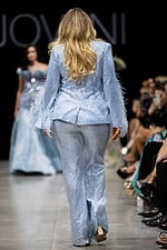 Model wearing Jovani 23162 powder blue pantsuit with feathered sleeves, view from the back.