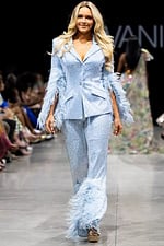 Model wearing Jovani 23162 powder blue pantsuit with feathered sleeves, view from the front.