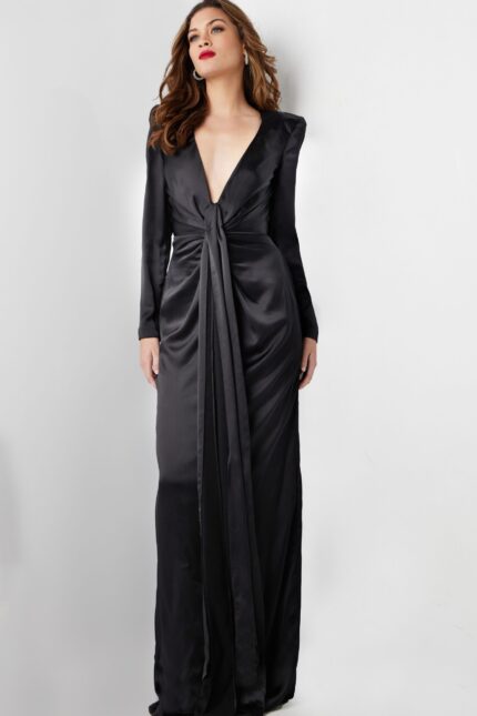 Model wearing Jovani 23180 elegant black gown with deep V-neckline and knot detail, front view.