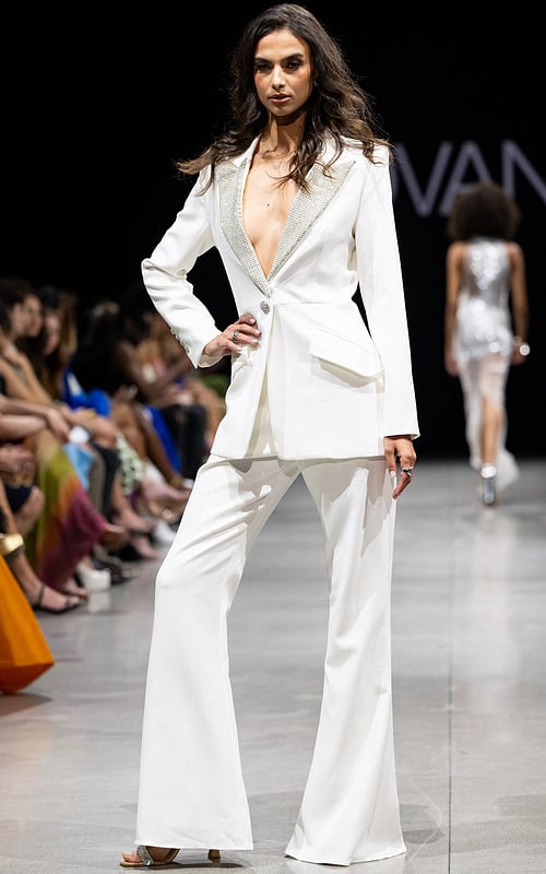 Model wearing Jovani 23336 white suit with embellished lapel and wide-leg pants.