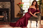 Model seated in Jovani 23398 burgundy dress, showcasing the dress's long flowing train.