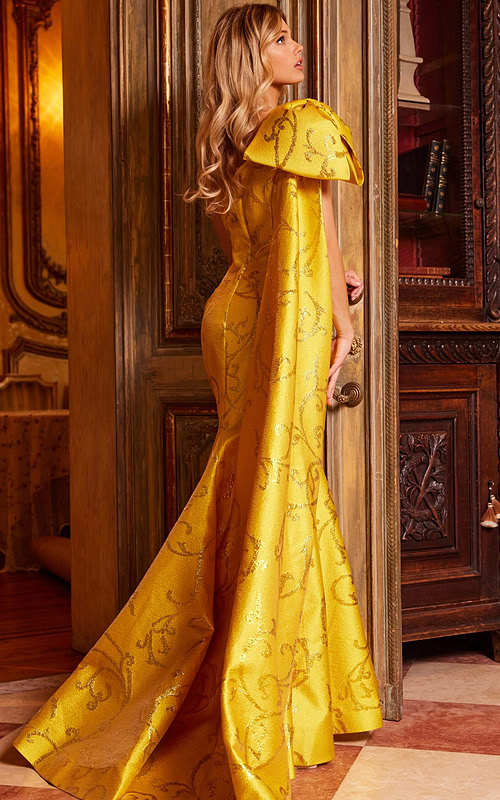 Model wearing Jovani 23742 yellow gown, back view showing flowing silhouette and train.