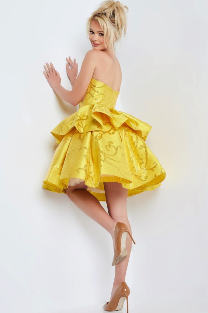 Model wearing Jovani 23743 yellow dress from the back, highlighting the strapless style and layered skirt.