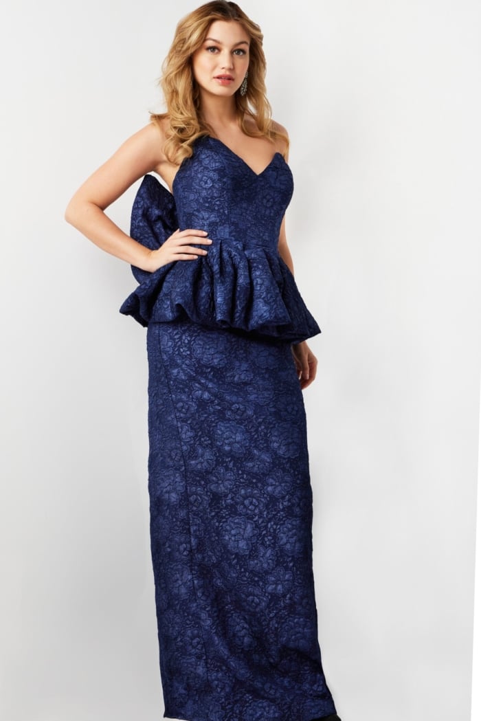 Model in Jovani 23849 navy gown with elegant peplum and sweetheart neckline.