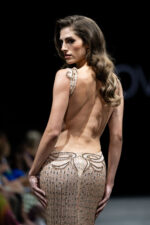 Model wearing Jovani 23896 blush dress with backless design, showcasing detailed embellishments, back view.