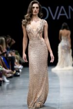 Model wearing Jovani 23896 blush dress with elaborate beading and deep V-neckline, front view.