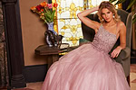 model showcasing Jovani 24051 blush gown seated with flowing skirt