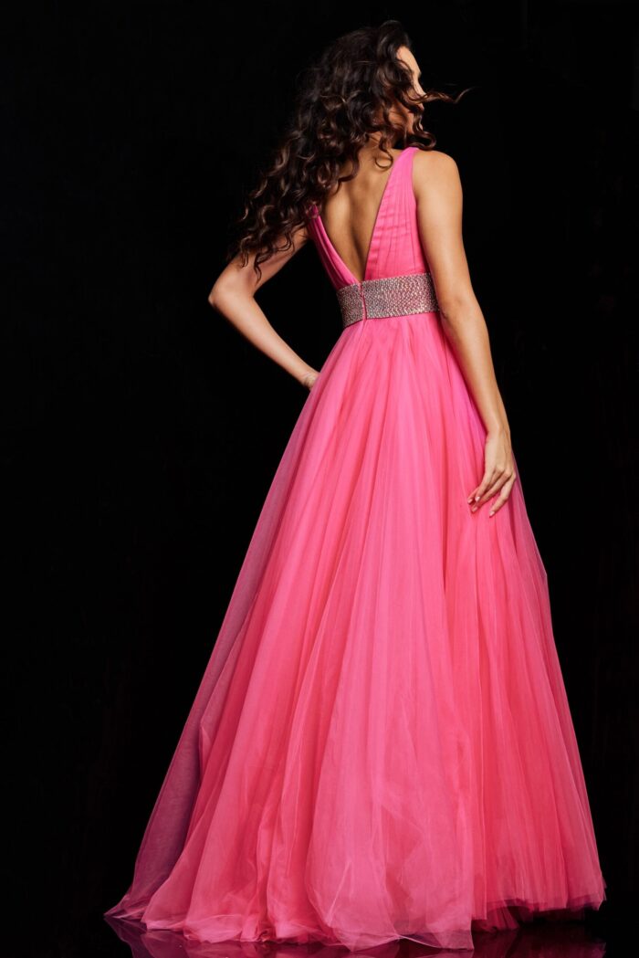 Model wearing Jovani 24564 hot pink gown with open back and embellished waistband, back view.