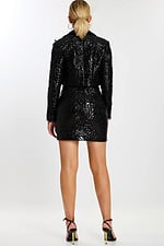 Back view of model in matching black embossed jacket and fitted skirt with floral texture.