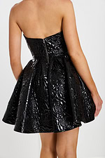 Close-up of shiny black embossed strapless dress with exposed zipper and structured skirt.