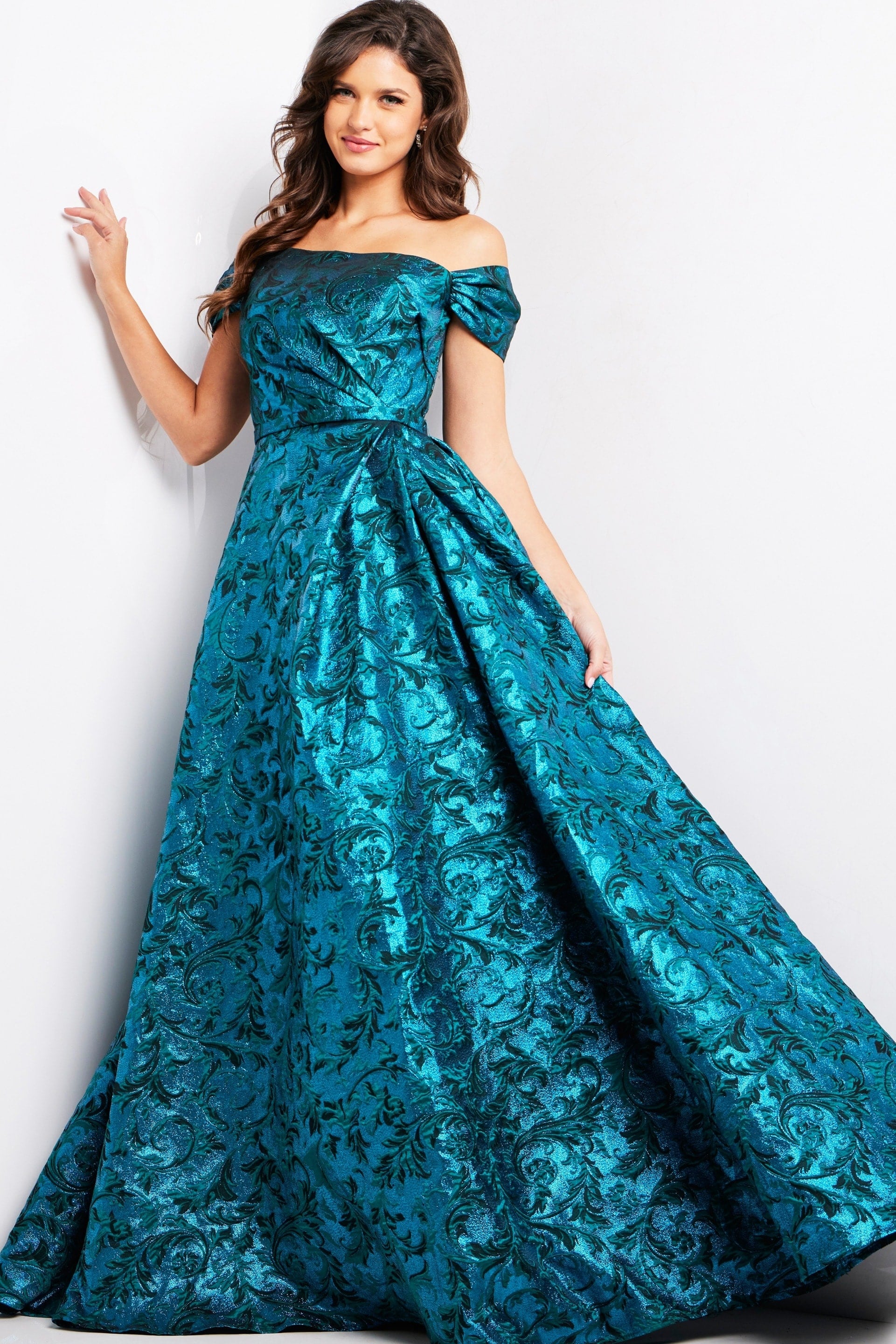 25665_PEACOCKTEAL_2019.jpg Model wearing Jovani 25665, a blue off-the-shoulder A-line gown with floral jacquard.