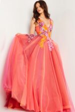 Model highlighting the details of Jovani 25800 orange gown with V-neckline and tulle layers.