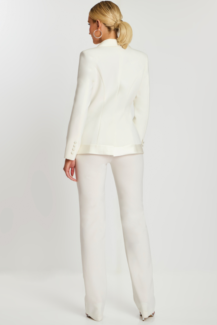 Back view of off-white fitted blazer and matching pants showing button cuff detail.