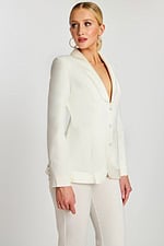 Model in off-white pantsuit featuring a smooth silhouette, satin accents, and long sleeves.