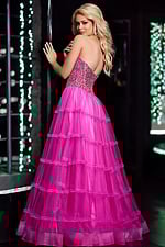 Model wearing Jovani 26011 pink gown showcasing back detailing and layered skirt.