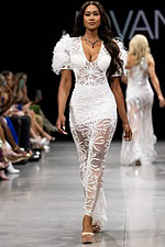 Model wearing Jovani 26057 white dress with embroidery and feathered sleeves, front view.