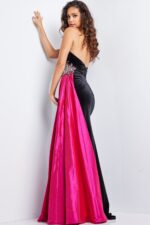 Model wearing Jovani 26117 black gown with fuchsia train, back view showcasing intricate embellishments.