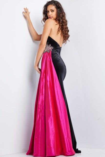 Model wearing Jovani 26117 black gown with fuchsia train, back view showcasing intricate embellishments.
