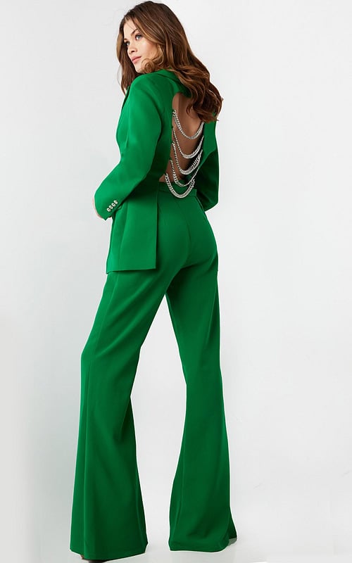 Model wearing Jovani 26144 green pantsuit with open back and chain detailing.